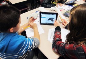 Two students examine a virtual 3-D model of a dinosaur bone from the museum's fossil collections.