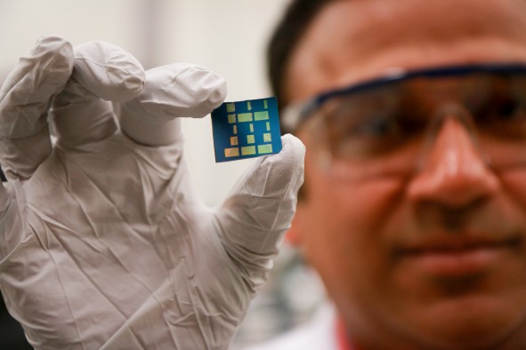University of Utah materials science and engineering associate professor Ashutosh Tiwari holds up a substrate layered with a newly discovered 2D material made of tin and oxygen. Tiwari and his team have discovered this new material, tin monoxide, which allows electrical charges to move through it much faster than common 3D material such as silicon. This breakthrough in semiconductor material could lead to much faster computers and mobile devices such as smartphones that also run on less power and with less heat.