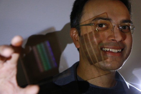 University of Utah electrical and computer engineering professor Rajesh Menon holds up the prototype of the first flat thin camera lens that he and his team developed. Menon and his doctoral students, Peng Wang and Nabil Mohamma, have developed a new kind of optical lens that is flat and ultrathin instead of the traditionally curved lens but can still focus all the colors of light to one point. The new lens can be used in cameras and other devices such as smartphones where the lens does not have to jet out of the body. Other applications of this potential lens system include medical devices in which thinner and lighter endoscopes can peer into the human body. It also could be used for drones or satellites with lighter cameras in which reducing weight is critical. Future smartphones could come with high-powered cameras that don’t require the lens jetting out from the phone’s thin body, such as the lens does now for the iPhone 6S.